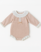 Body rosa em tricô para bebê, com gola rendada branca e laço rosa no centro, trazendo charme e conforto para os pequenos.
