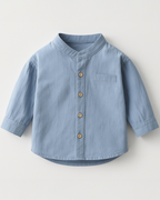 Camisa infantil azul com gola padre e botões frontais, perfeita para looks clássicos e charmosos.