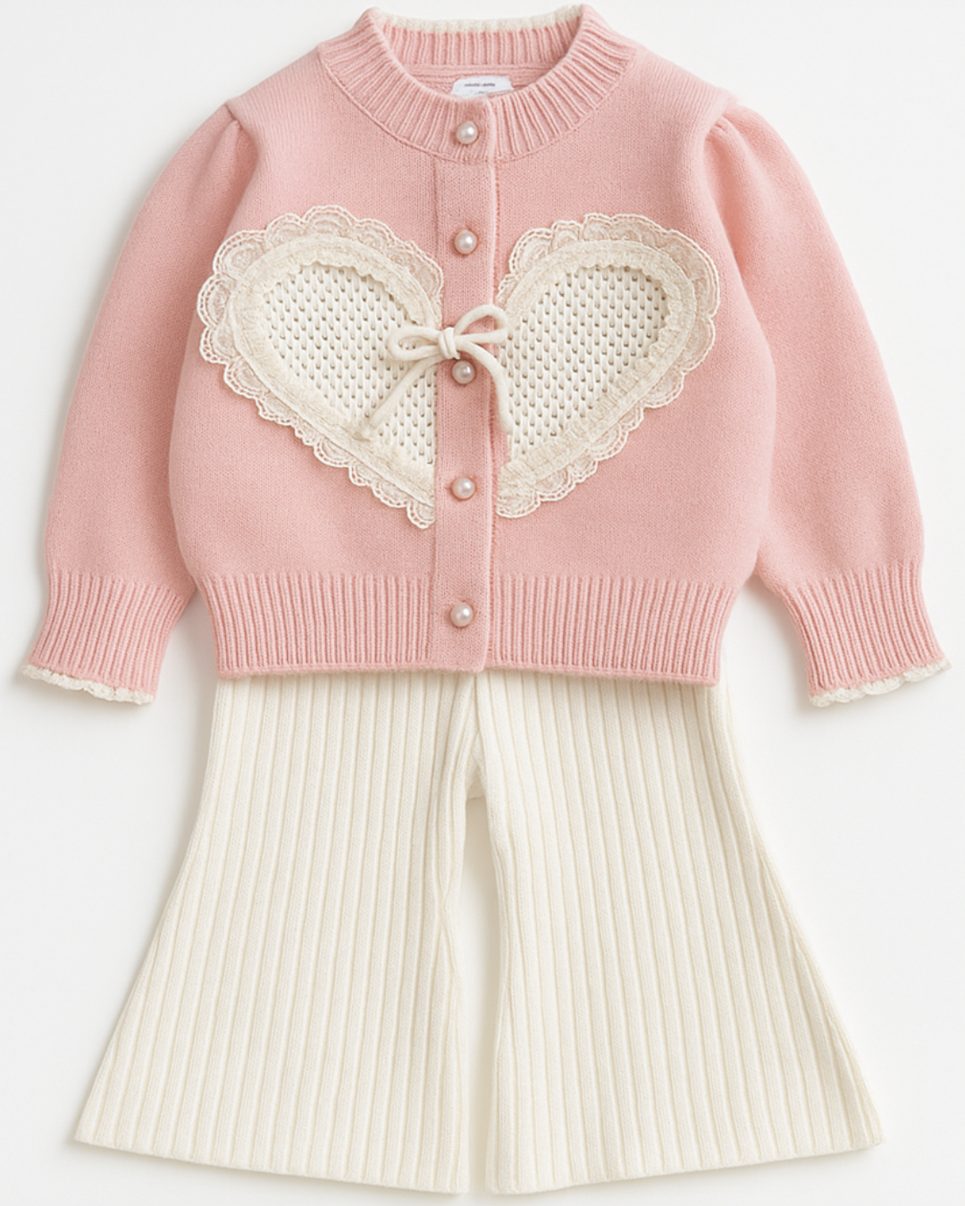 Conjunto infantil feminino com cardigan rosa de tricô com aplicação de coração rendado e calça off-white de malha canelada.