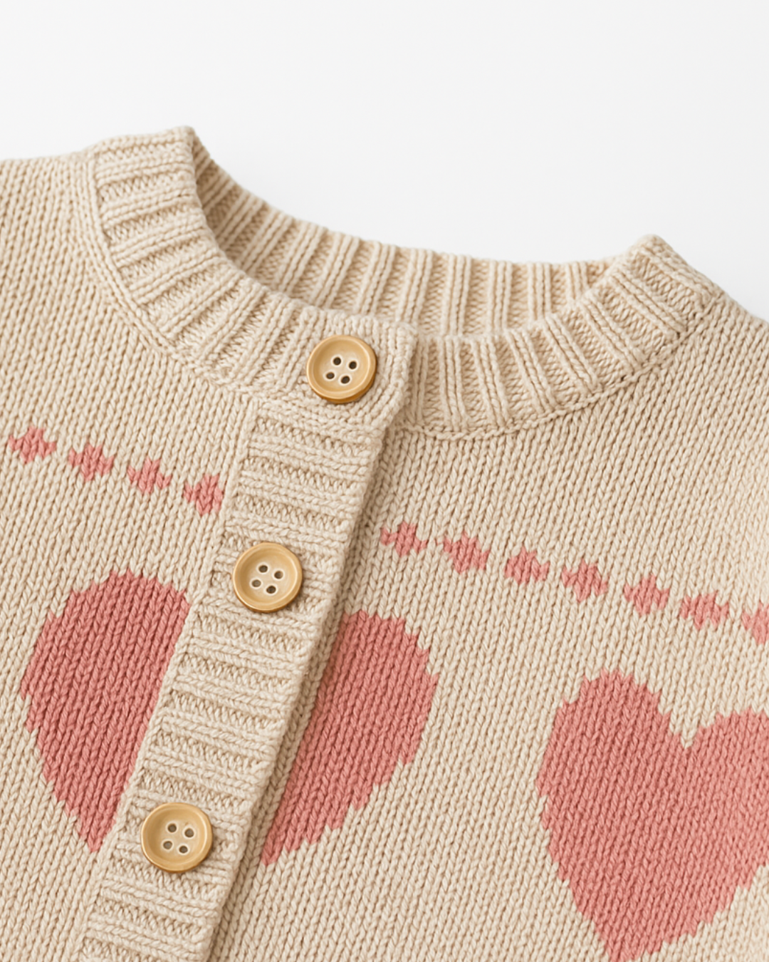 Macacão infantil de tricô na cor bege com estampa de corações rosa e forro interno macio. Perfeito para dias frios.