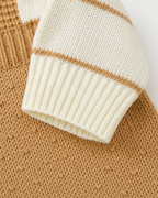 Detalhe da manga listrada em tricot bege e creme de macacão infantil